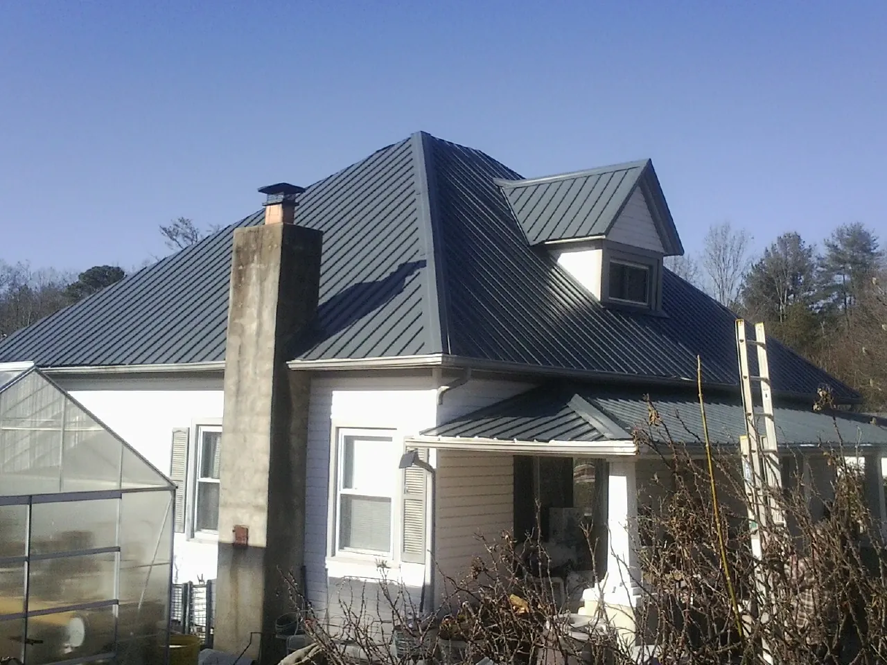Dark blue standing seam metal roof on a white farmhouse with dormer — Slate & Tile Roof Repair by Roofing Brothers in Topanga