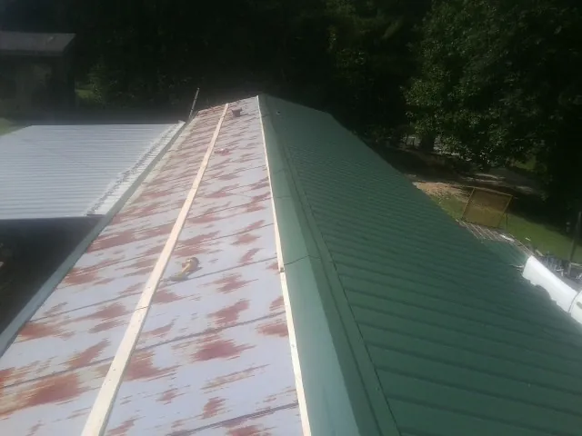 Old rusted panels beside newly installed green metal roofing — Wind Damage Roof Repair by Roofing Brothers in Topanga