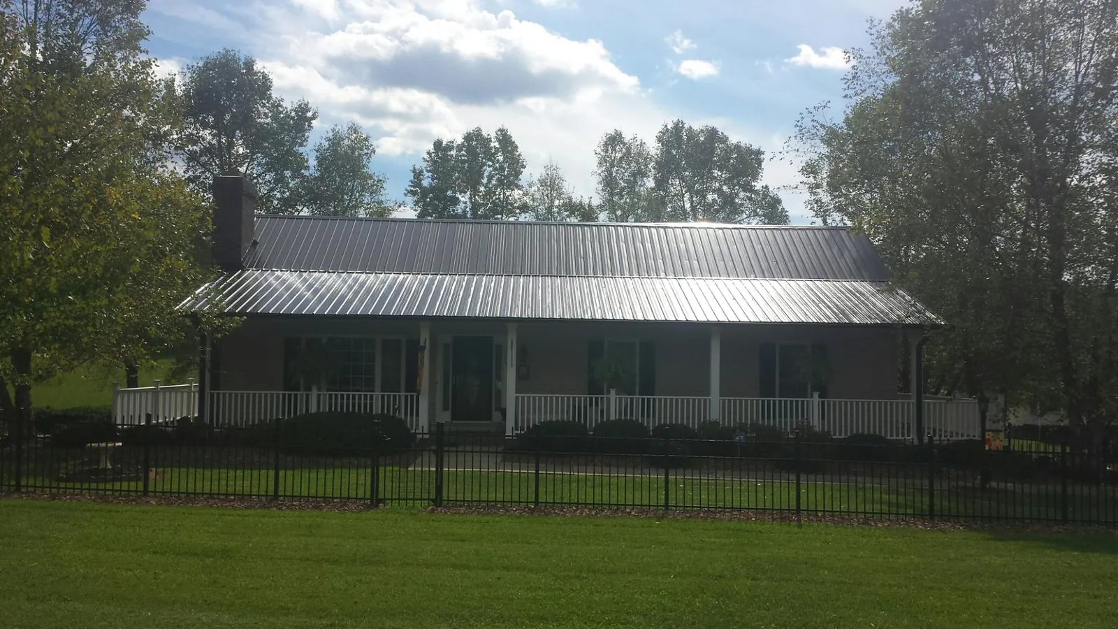 Gray metal roof on a brick ranch with a full width front porch — Gutter Guard Installation work by our crew in Topanga