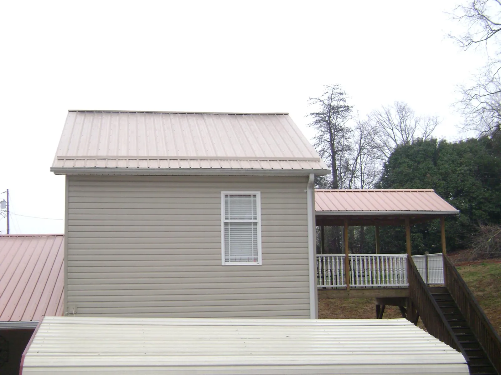 Tan metal roofs on a two story addition and attached porch, from a Roof Replacement job in Topanga