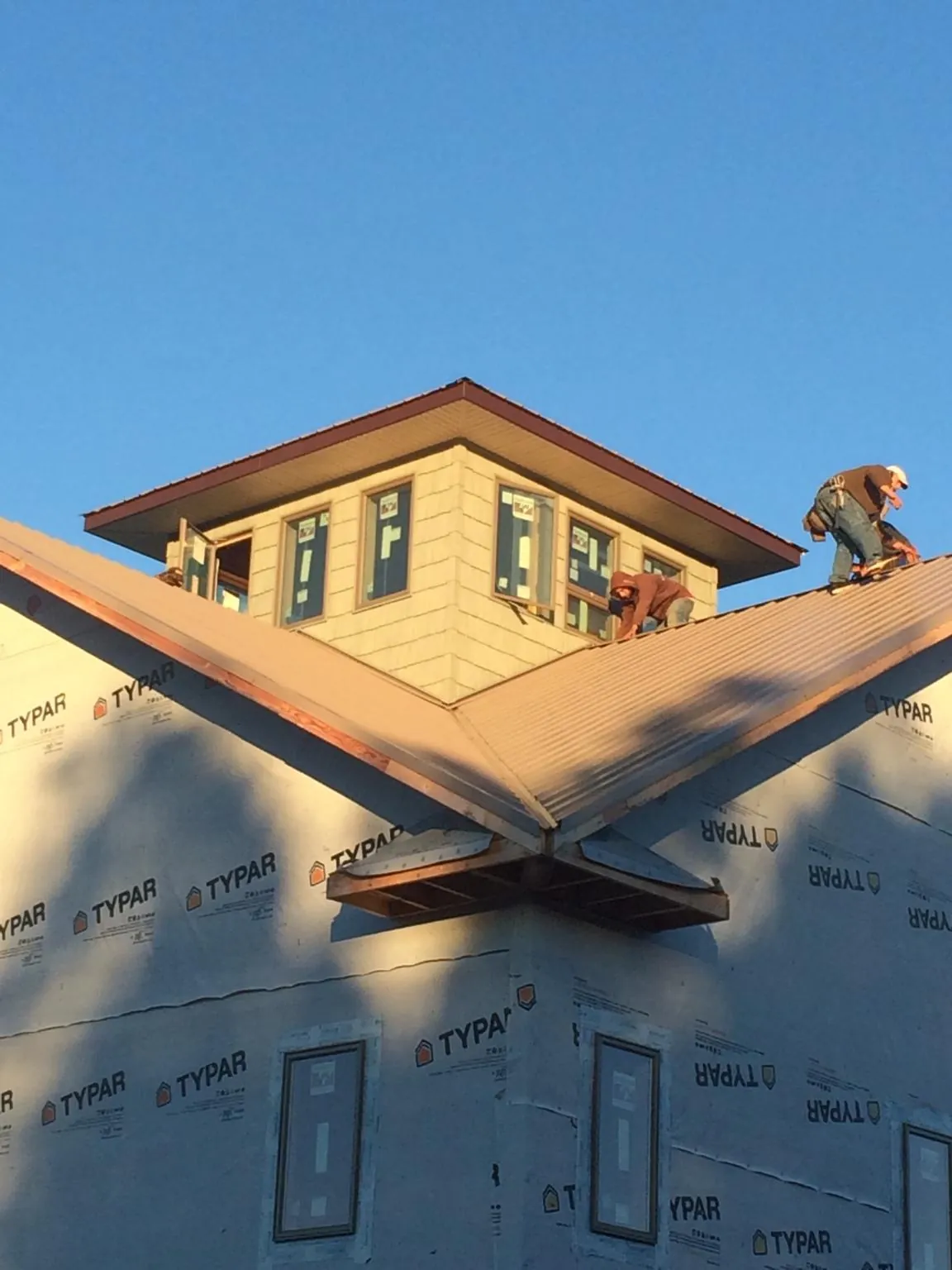 Roofers working around a rooftop cupola on a new metal roof at sunset — Roof Waterproofing in Topanga by Roofing Brothers